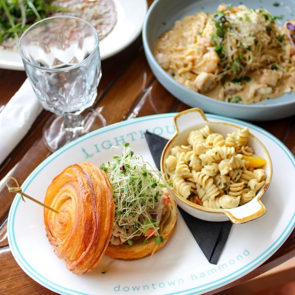 Lighthouse Coastal Brasserie seafood croissant sandwich with sprouts, pasta salad, and creamy pasta.
