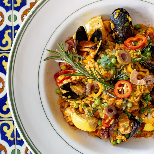 Lighthouse Coastal Brasserie's seafood paella with mussels, lemon, peppers, and rosemary on a white plate.
