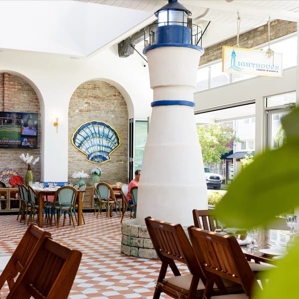 Lighthouse Coastal Brasserie interior with a large decorative lighthouse, brick arches, and dining tables.